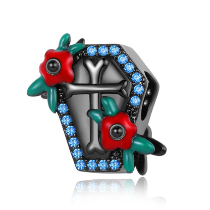 Decorative brooch with red flowers, green leaves, and blue gemstones on a white background, coffin pandora style charm pendant. Gothic style, halloween theme 