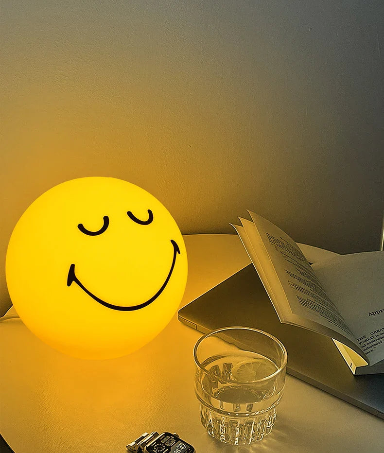 Smiley face night light on a table with a glass and book