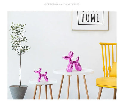 Pink balloon dog sculptures on small tables with a yellow chair and plant in a minimalistic room.
