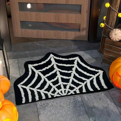 Spider web doormat on a stone floor with pumpkins and Halloween decorations.