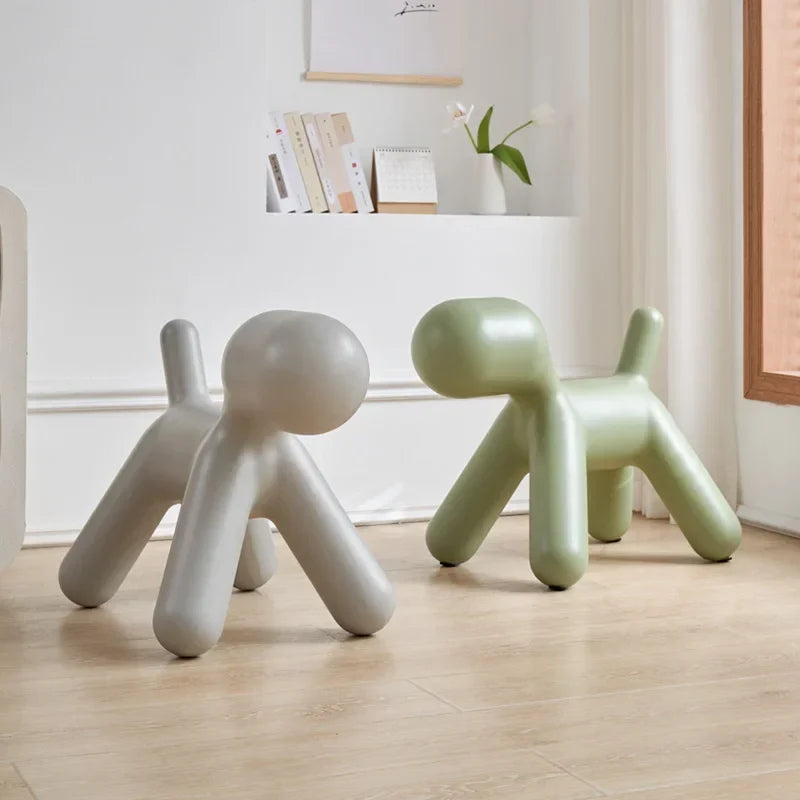 Two modern dog-shaped stools in a room with a shelf in the background.