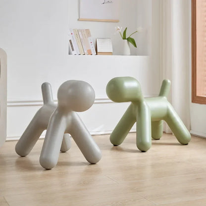 Two modern dog-shaped stools in a room with a shelf in the background.
