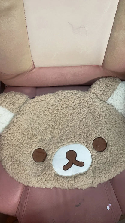 Plush toy with a bear face design on a pink surface