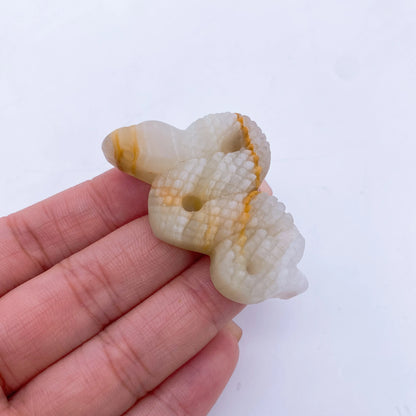 A collage of various crystal snake statues in different colors held in a person's hand.