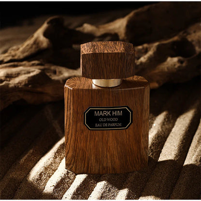 Wooden perfume bottle labeled 'Mark Him Old Wood Eau de Parfum' on a textured surface.