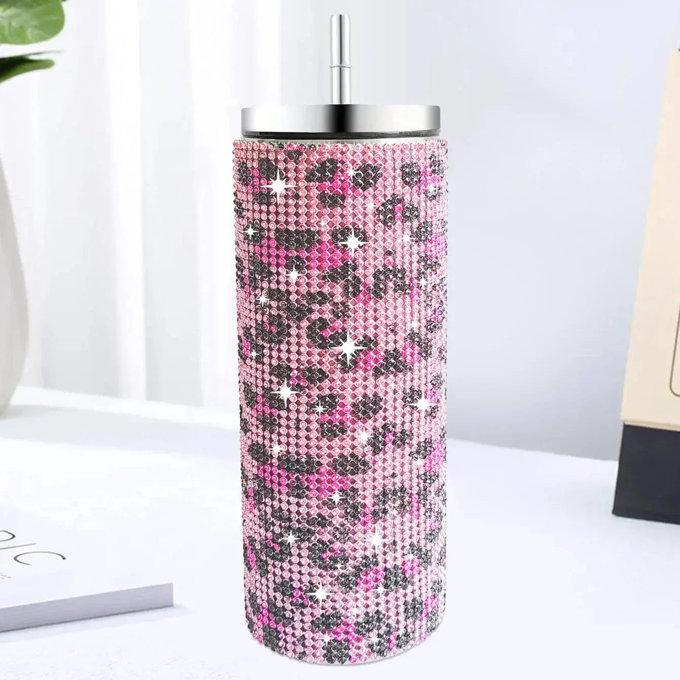 Pink and black patterned tumbler with a silver lid on a white surface.