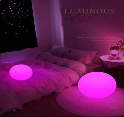 Two glowing pink spherical lights on a bed with a 'Luminous' sign in the background.