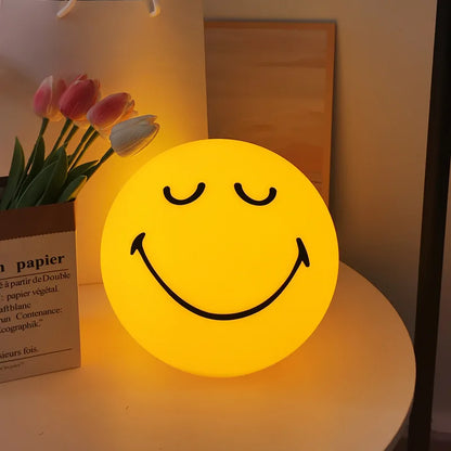 Smiley face night light on a surface with tulips in the background