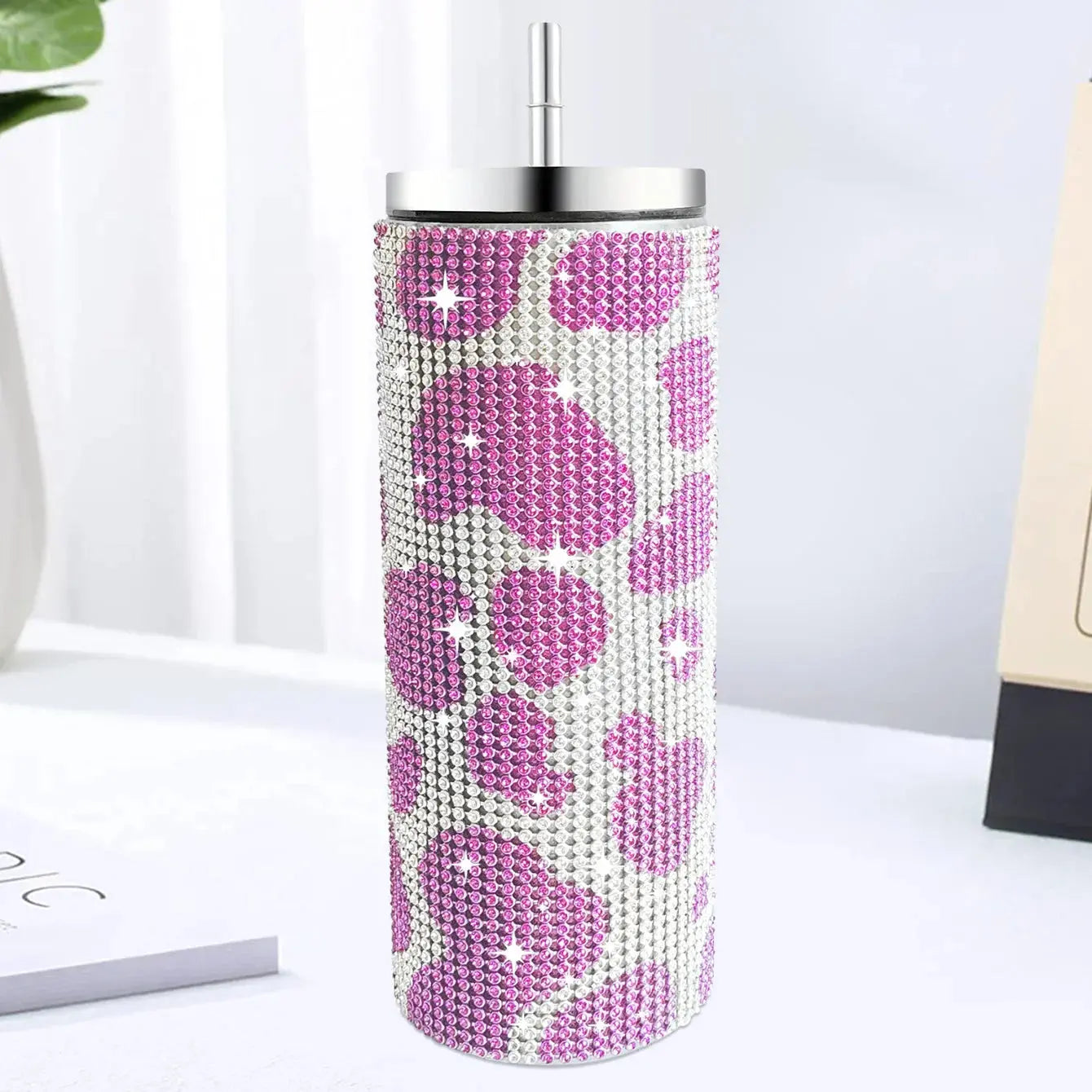 Tumbler with pink leopard print and rhinestone details on a white surface.