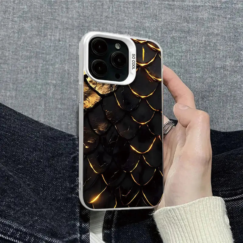 Hand holding a phone with a black and gold patterned case against a gray background