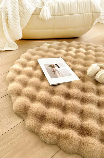 Round textured beige rug on a wooden floor with a magazine and headphones on top.