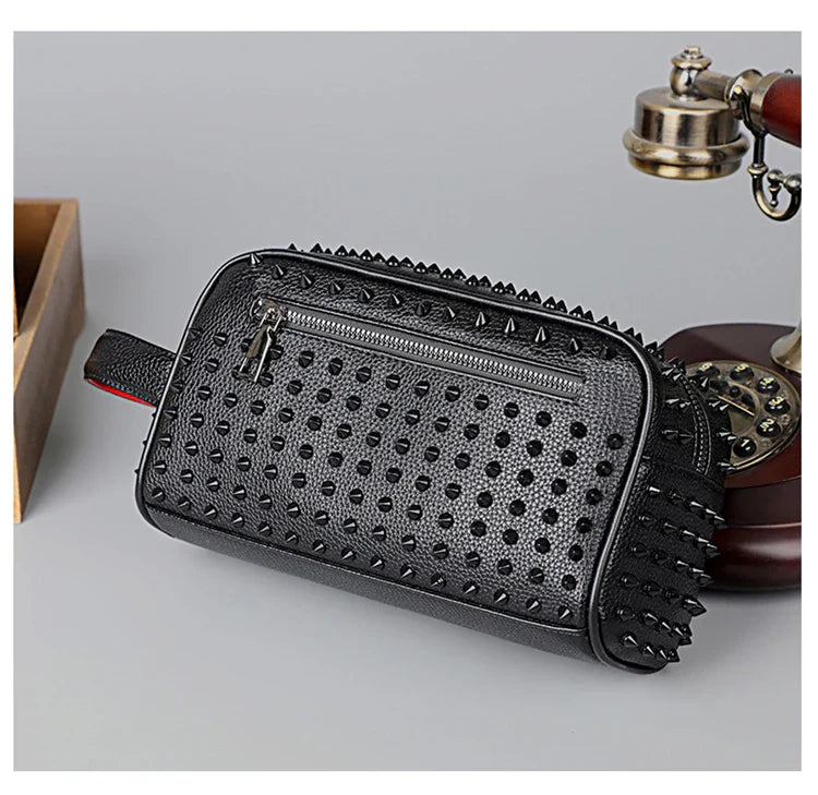 Black studded clutch bag on a light gray background with a vintage phone and wooden box.