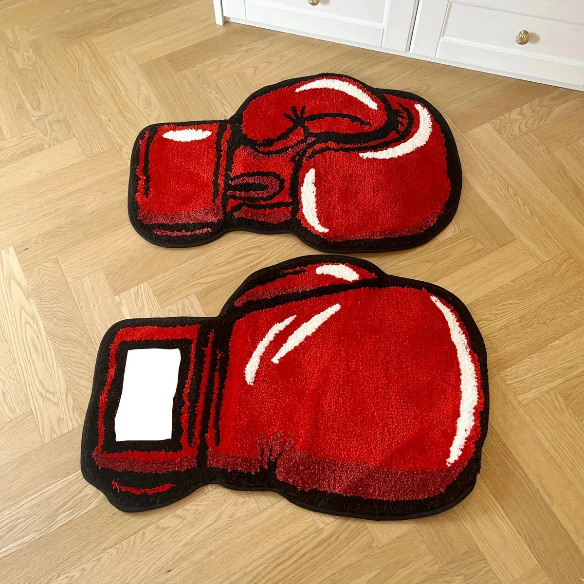 Two red boxing glove mats on a wooden floor.