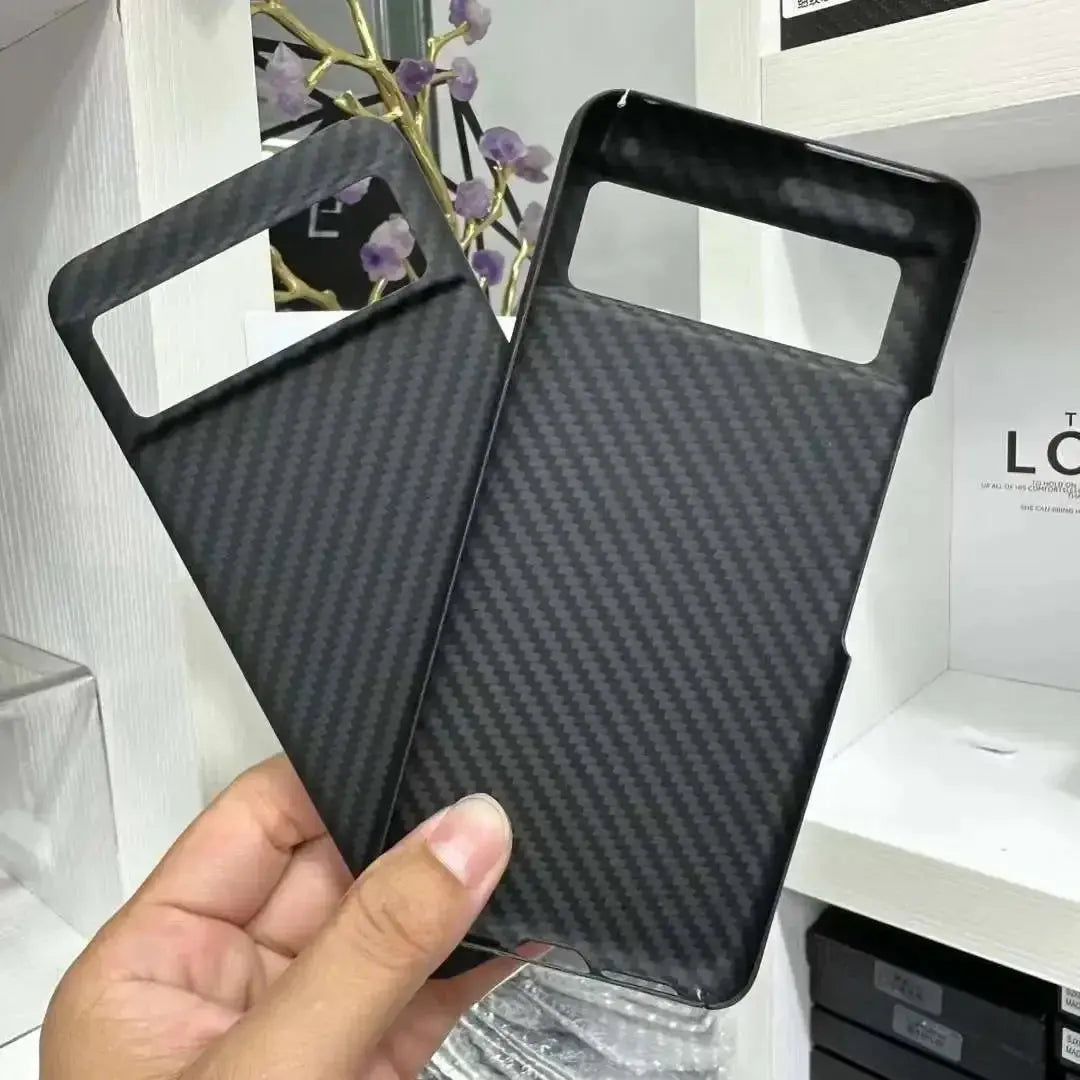 Carbon fiber texture phone case held by a hand with a blurred indoor background