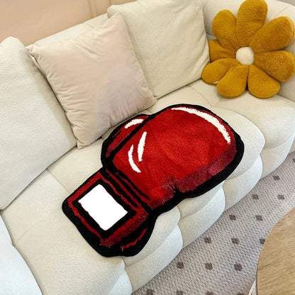 Red boxing glove-shaped rug on a beige sofa with decorative pillows.