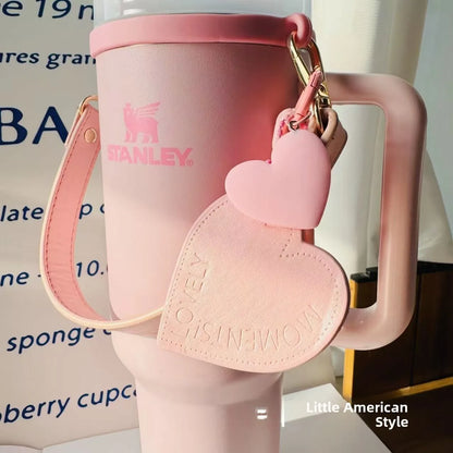 Pink Stanley mug with heart-shaped keychain on a blurred background