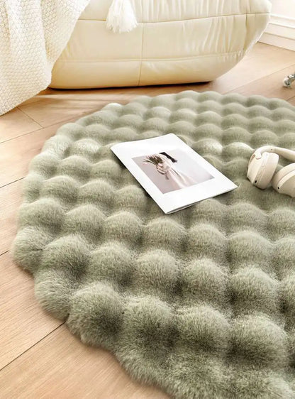 Round green rug on a wooden floor with a photo and small plant on top