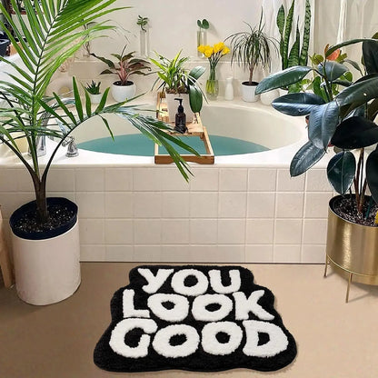 Bathroom with a bathtub, plants, and a 'You Look Good' rug. bath mat