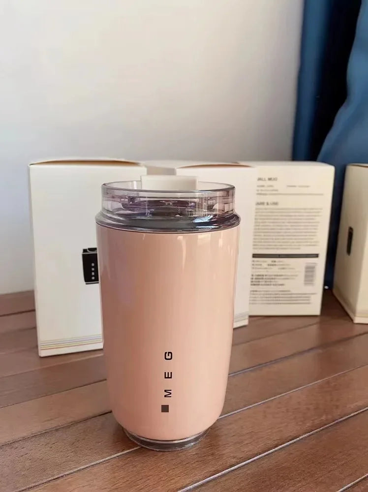 SMEG Pink tumbler with 'MEG' branding on a wooden surface with boxes in the background
