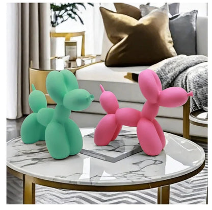 Two balloon dog sculptures, one green and one pink, on a marble coffee table in a living room.